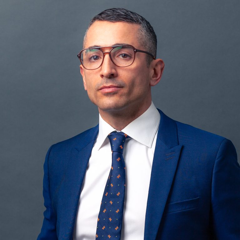 Headshot of lawyer Steven Nicoletta in blue suit on grey background