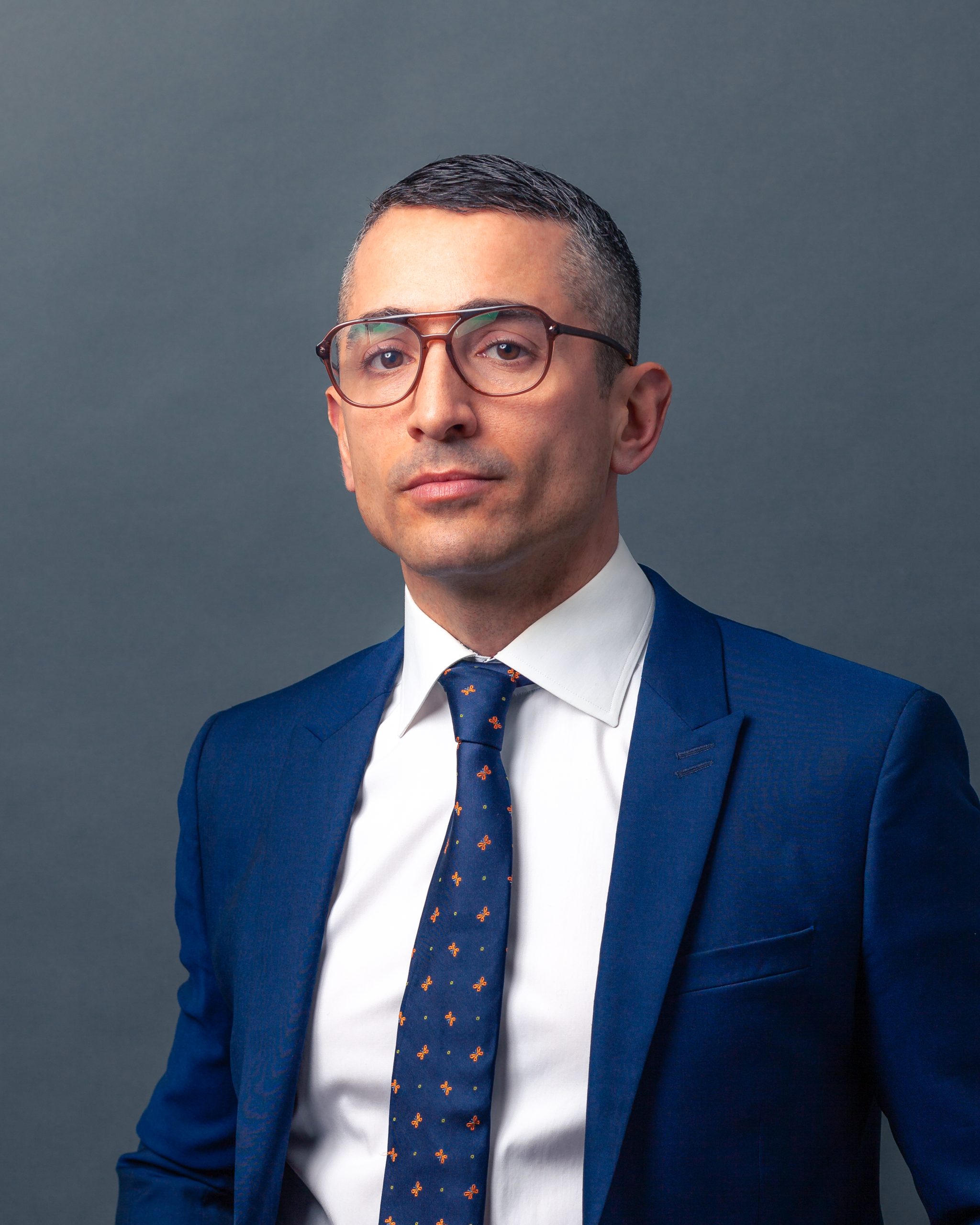 Headshot of lawyer Steven Nicoletta in blue suit on grey background