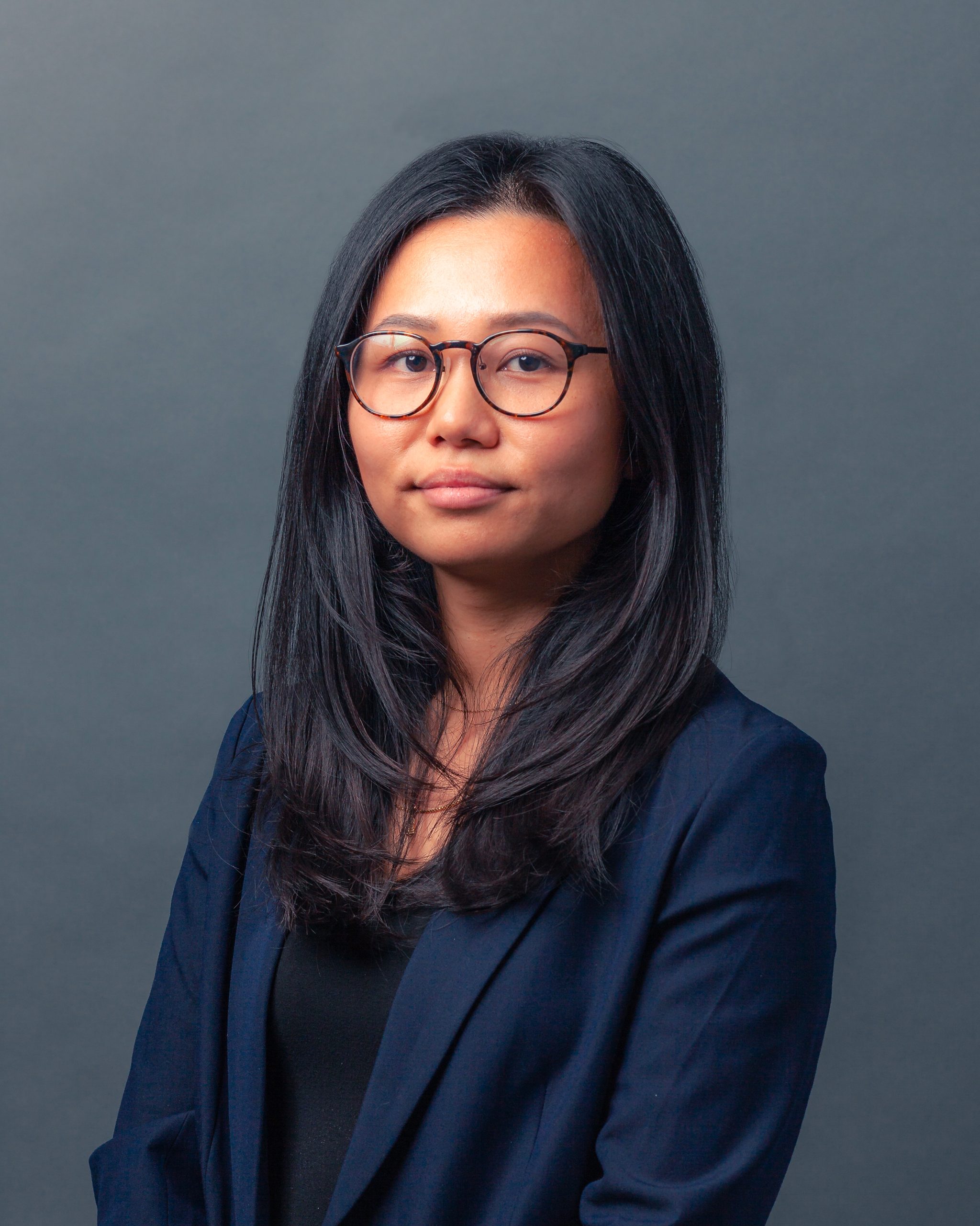 Headshot of lawyer Myle Nguyen in blue suit on grey background
