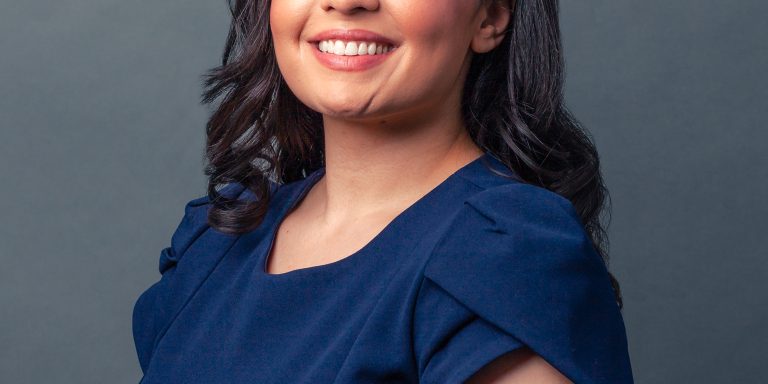 Headshot of lawyer Lida Rawofi in blue suit on grey background